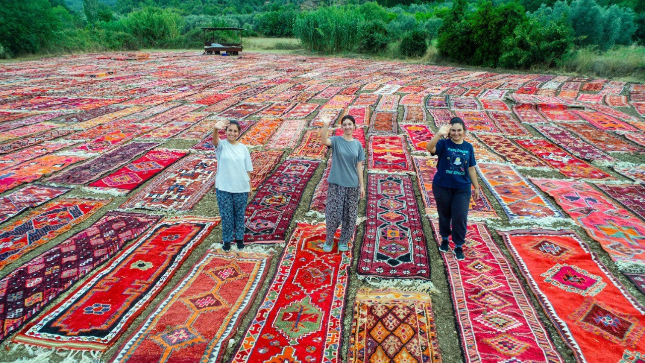 Women workers lay rugs in fields in Antalya, creating colorful scenes